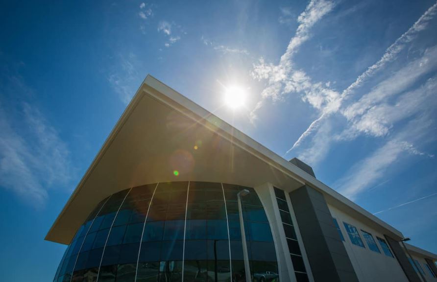 Large building with tall glass wall and a sunny blue sky