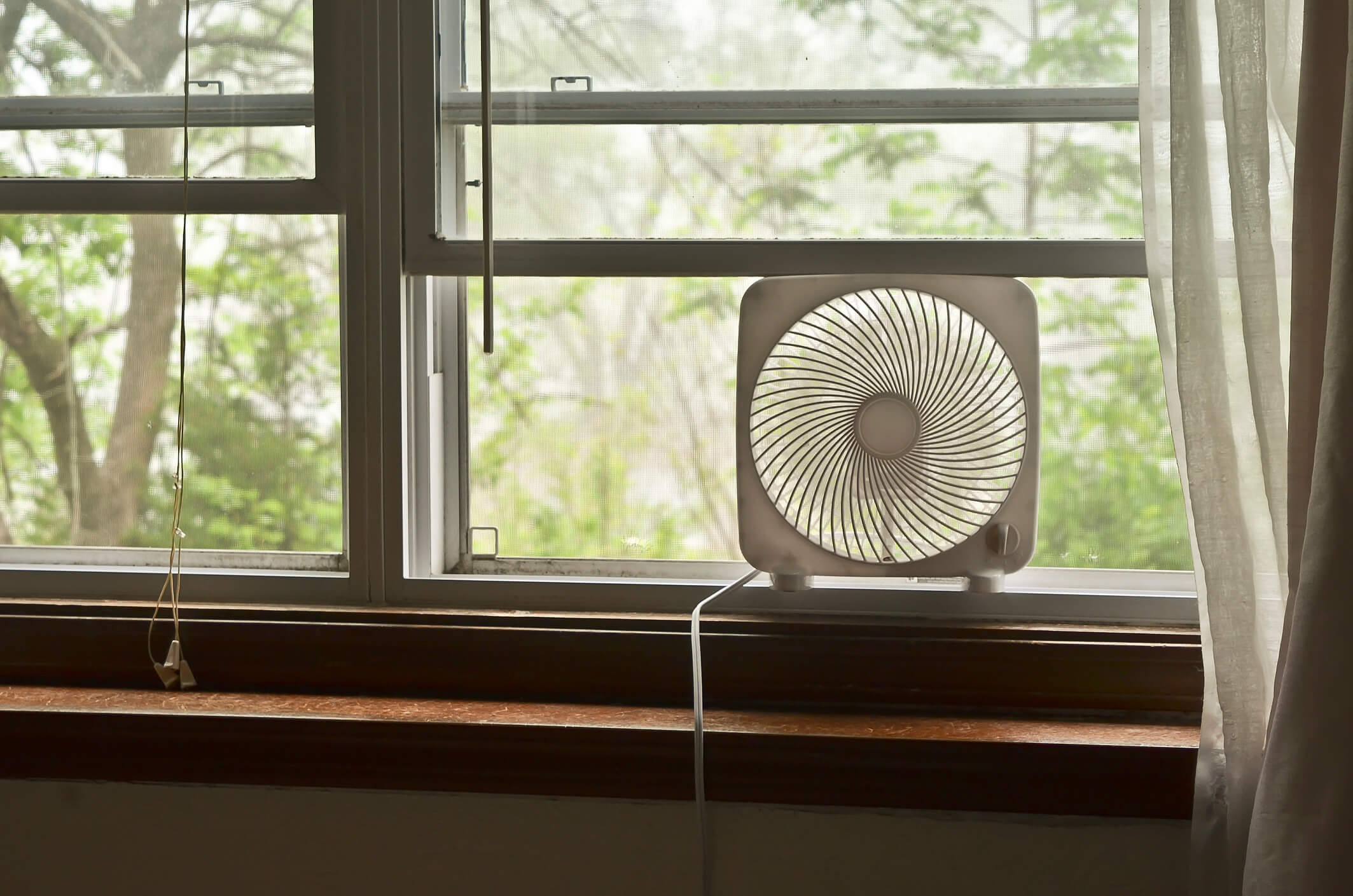 a fan positioned in an open window to keep a home cool